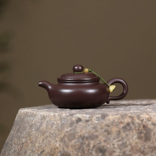 Purple teapot with decorative elements on a stone surface