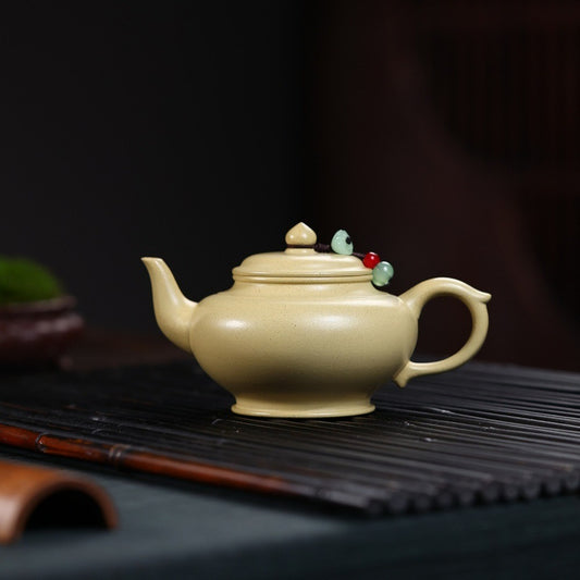 Cream-colored teapot with decorative elements on a dark surface