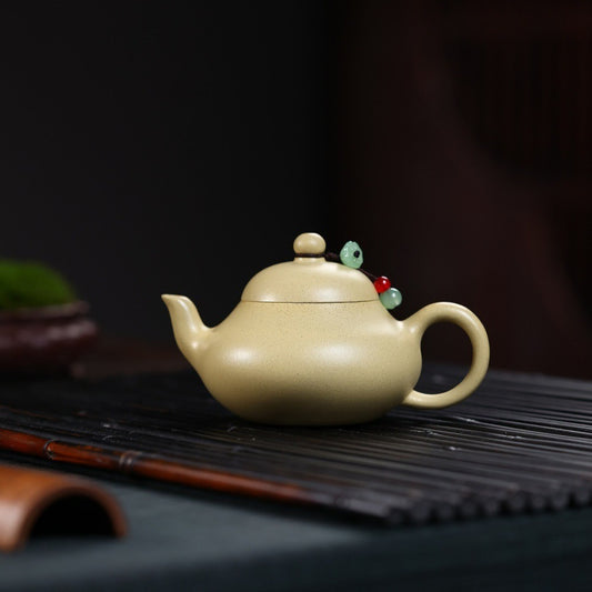 Beige ceramic teapot with decorative elements on a dark surface