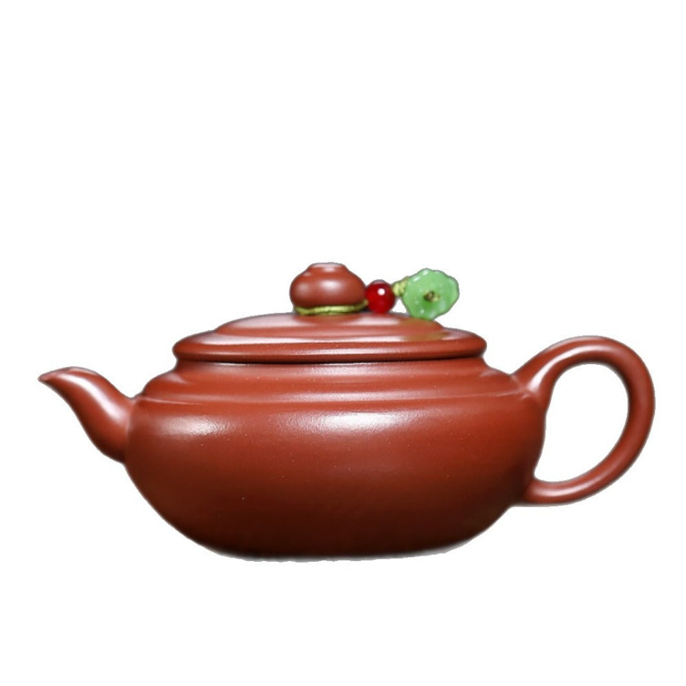 Red clay teapot with decorative lid on a white background