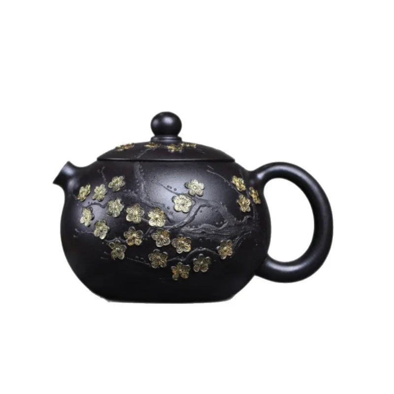 A black ceramic teapot decorated with gold-toned floral motifs, shown against a plain white background.