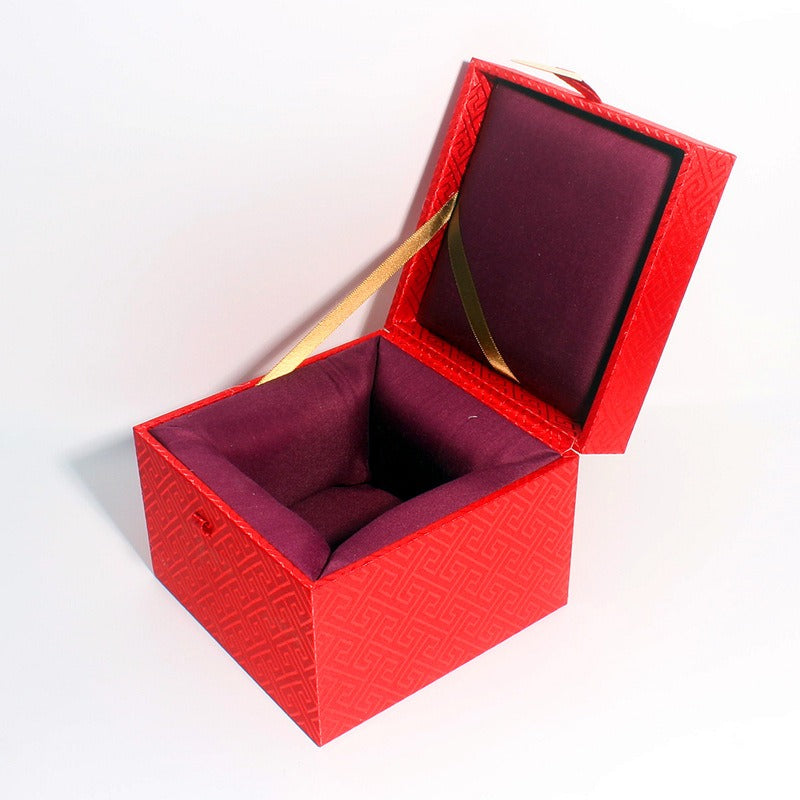 Three ornate cubic gift boxes with traditional East Asian-inspired designs on a wooden table