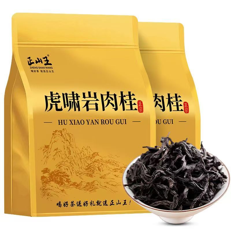 Two gold tea bags labeled 'HU XIAO YAN ROU GUI' with a small white bowl of dark dried tea leaves in front, on a white background.


