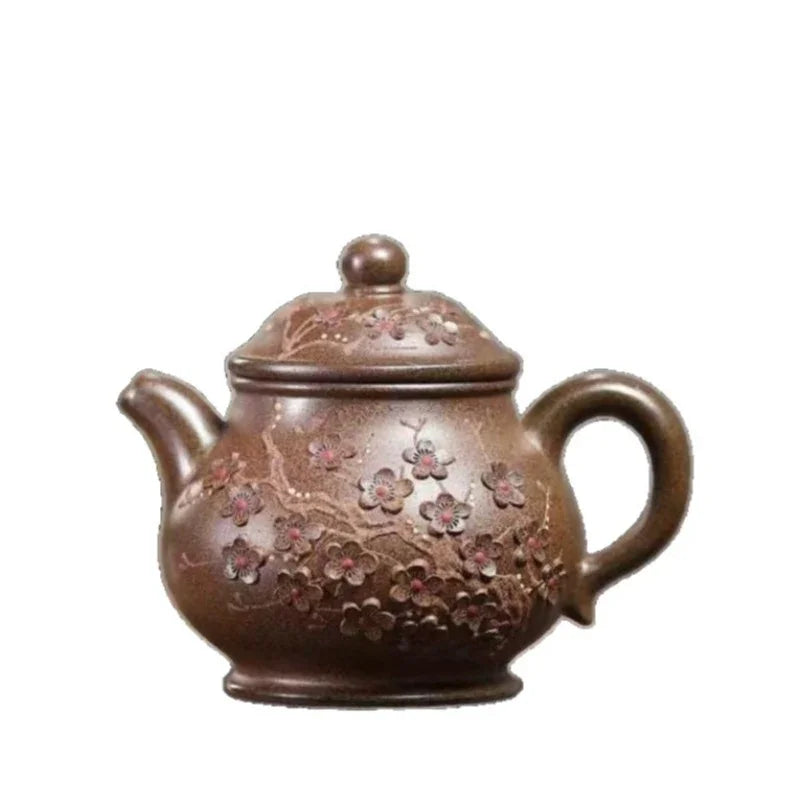 A brown ceramic teapot with a lid, featuring embossed floral patterns in pink and beige tones, shown against a plain white background.

