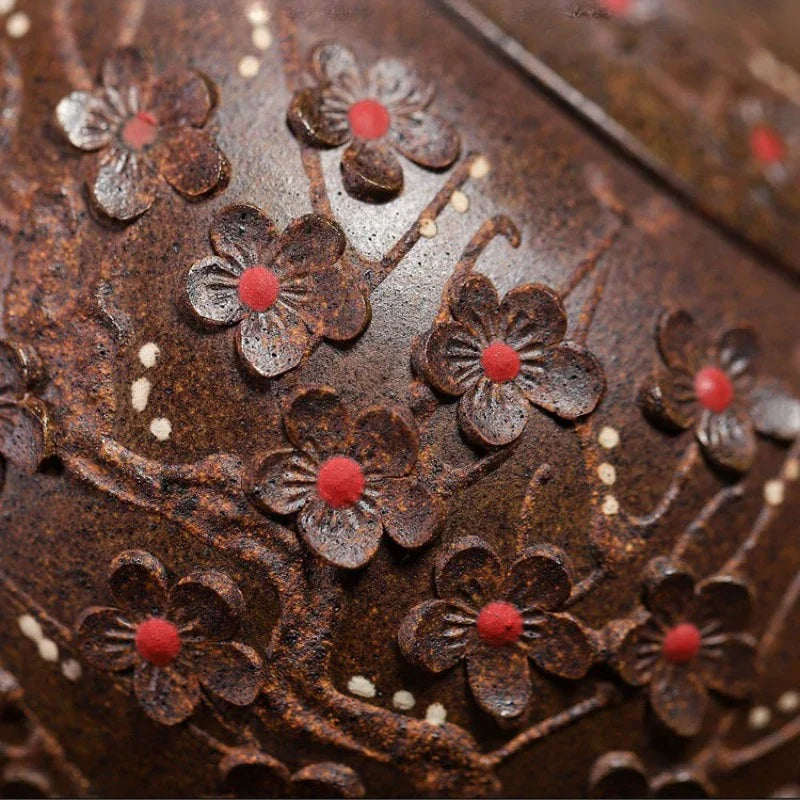 Close-up of a dark brown textured surface with embossed floral motifs featuring red centers and small white speckles.

