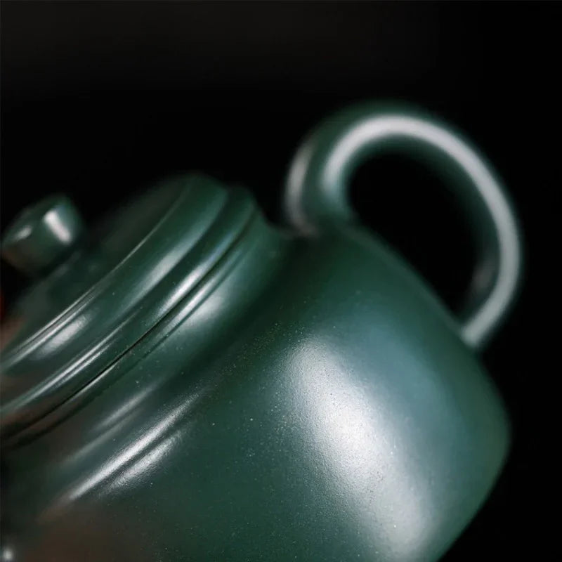 Close-up of a green teapot on a black background

