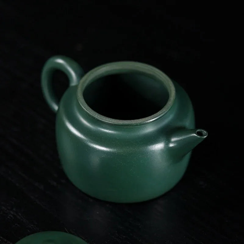 Green ceramic teapot on a dark surface

