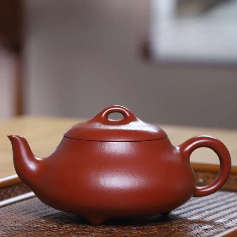 Red teapot on a wooden surface with a blurred background

