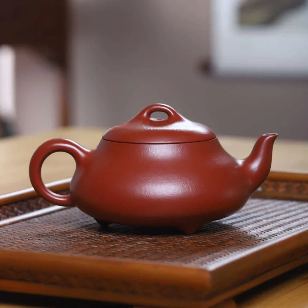 Red teapot on a woven mat with a blurred background

