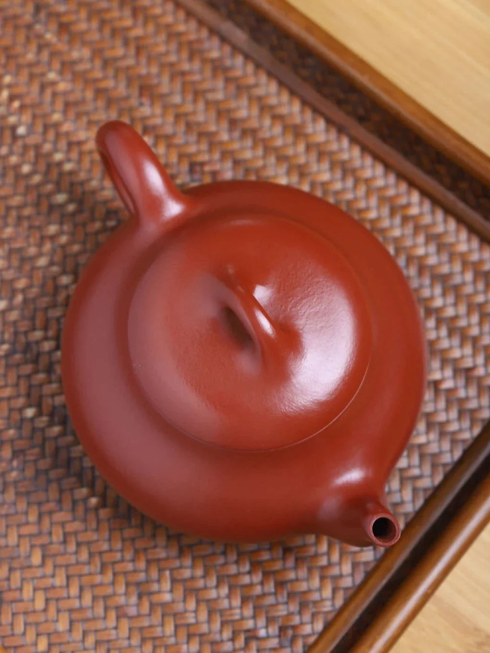Red ceramic teapot on a textured woven surface

