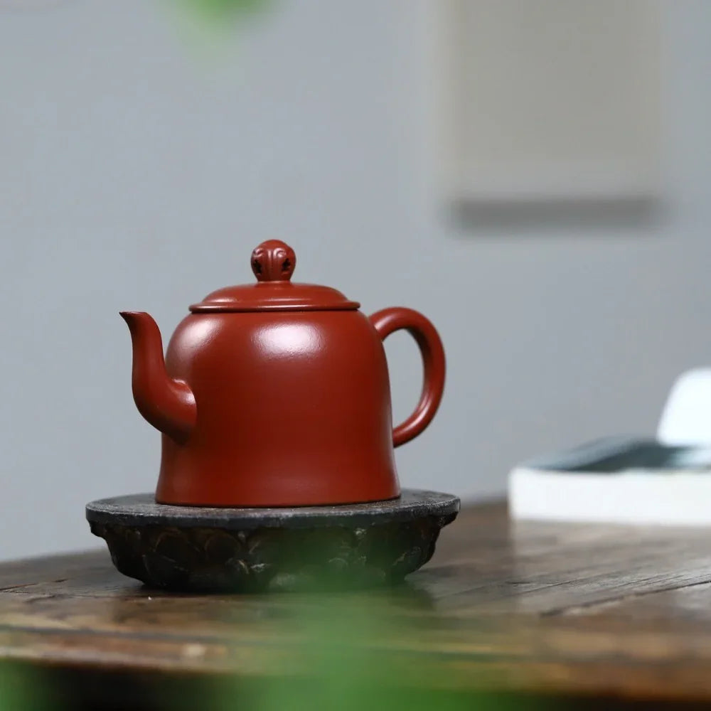 Red teapot on a black coaster with a blurred background

