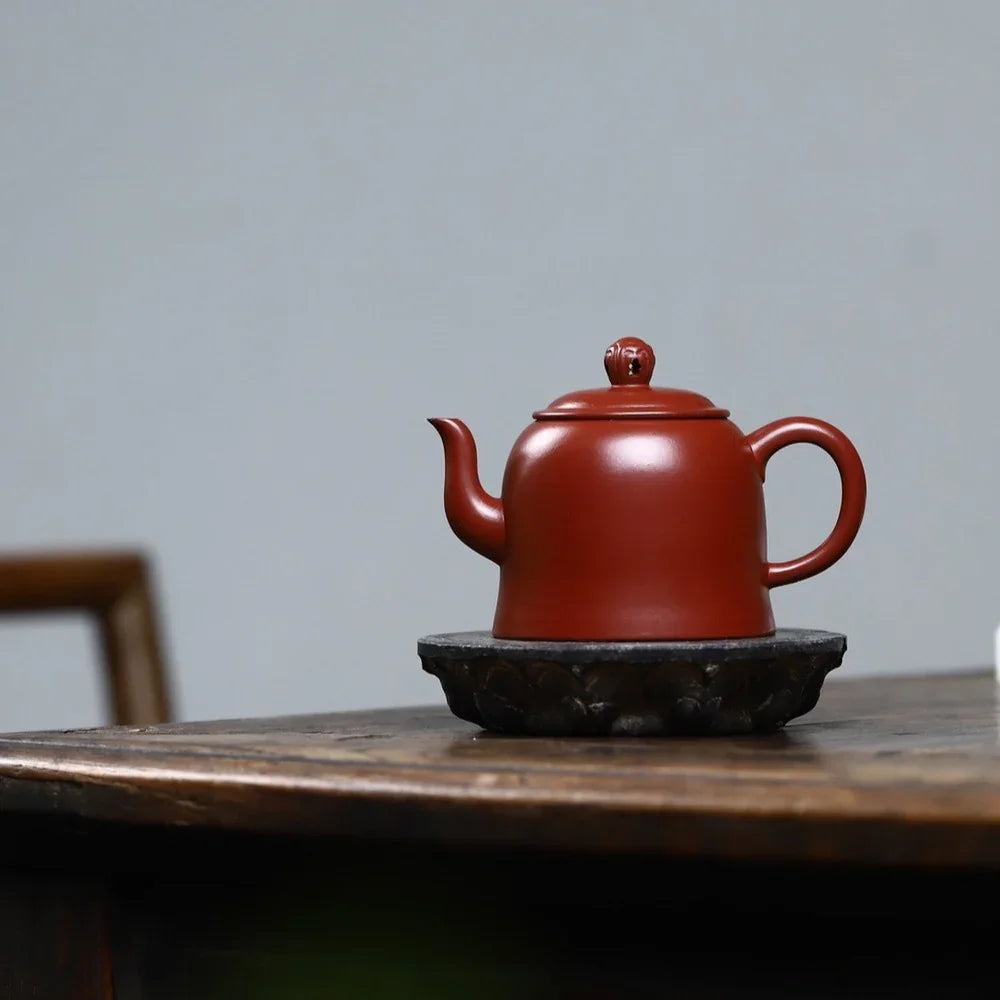 Red teapot on a wooden table with a gray background

