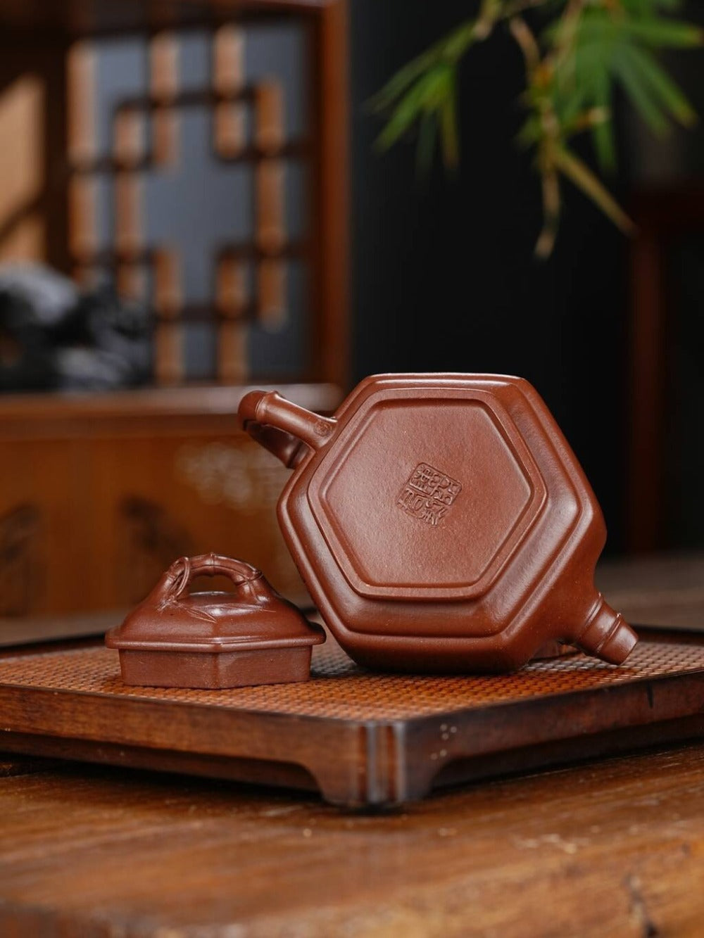 Hexagonal brown ceramic teapot on a wooden surface with a blurred background

