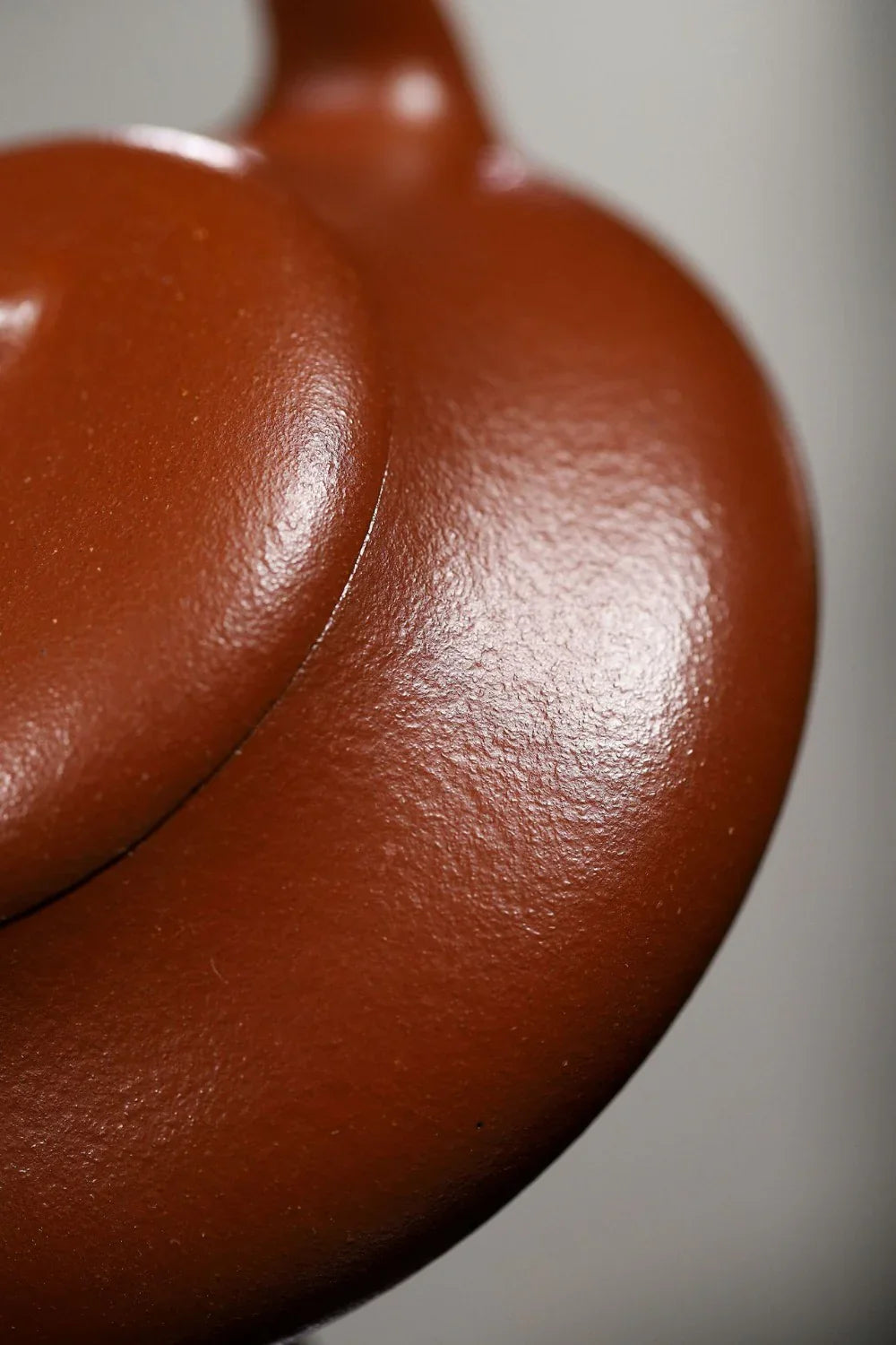 Close-up of a red ceramic teapot with a lid on a gray background

