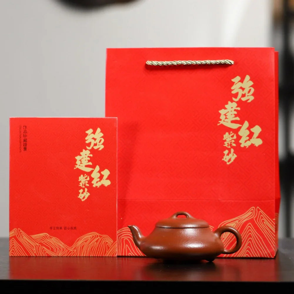 Red gift box with teapot on a reflective surface

