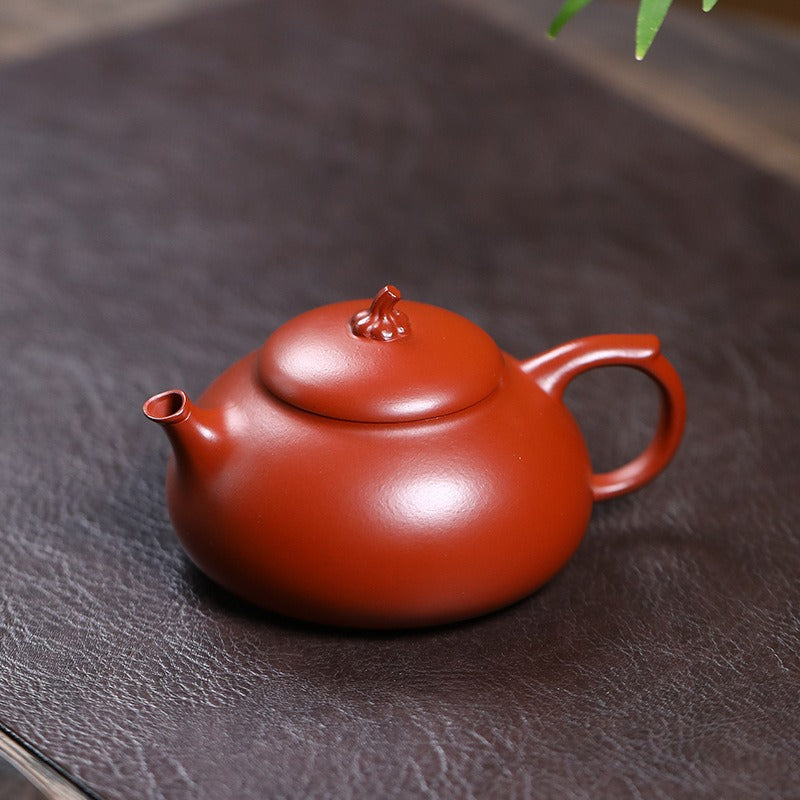 Red ceramic teapot on a dark brown surface

