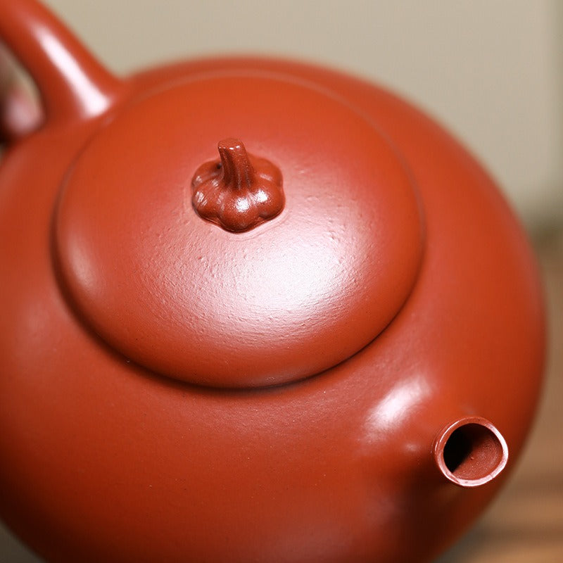 Close-up of a red ceramic teapot with a blurred background

