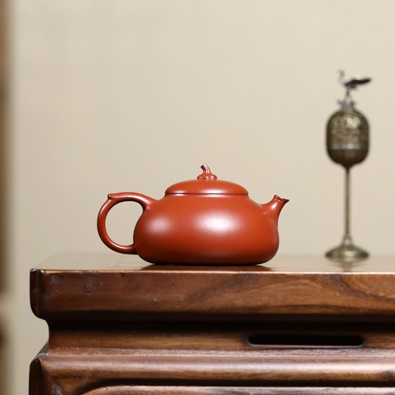 Red teapot on a wooden surface with a blurred background

