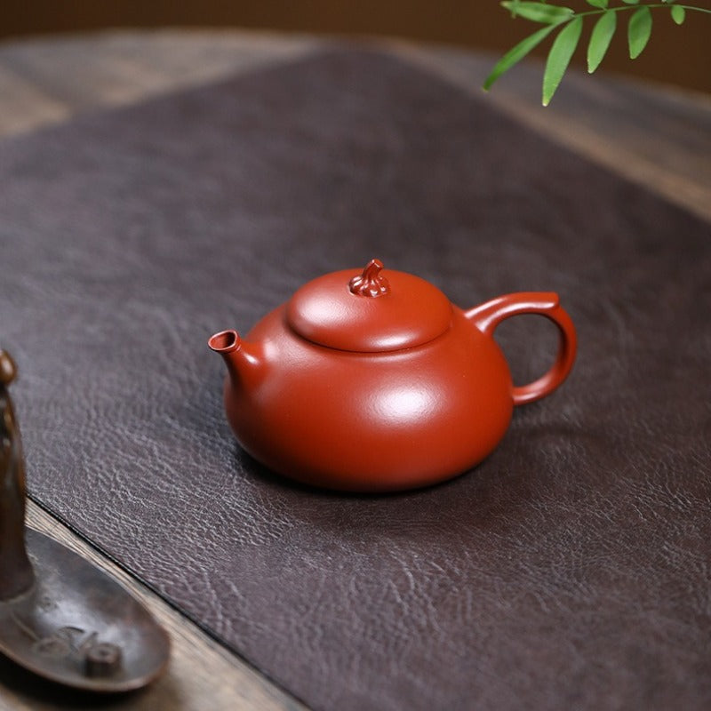 Red teapot on a textured surface with a blurred background


