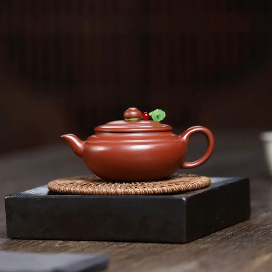 Red ceramic teapot with decorative elements on a dark surface

