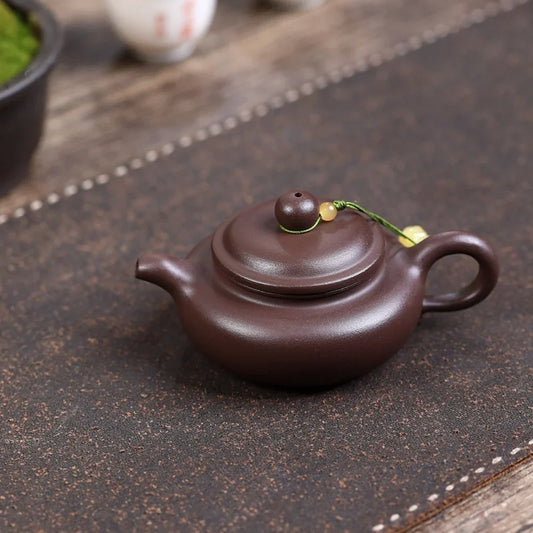 Purple clay teapot on a textured surface

